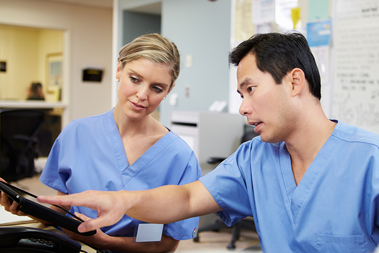 Nurses speaking to while pointing at tablet