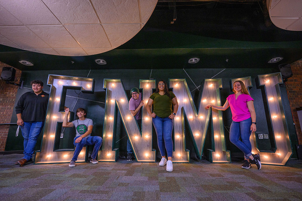 Students in front of ENMU sign in Greyhound Lounge