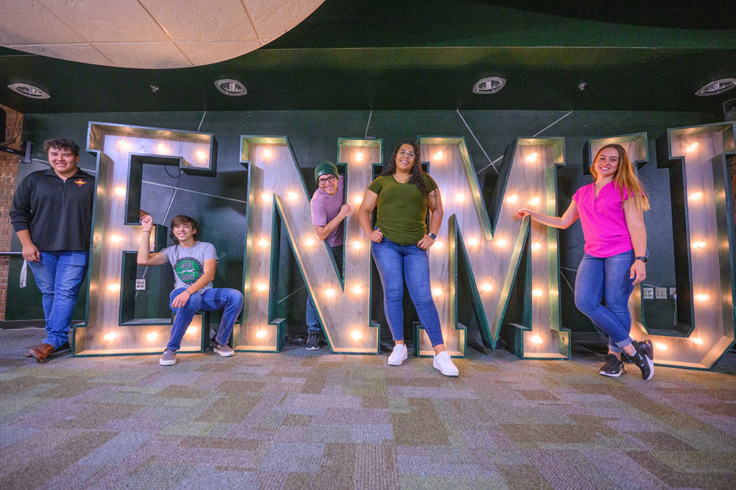 Students in front of ENMU sign in Greyhound Lounge