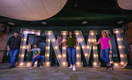 Students in front of ENMU sign in Greyhound Lounge